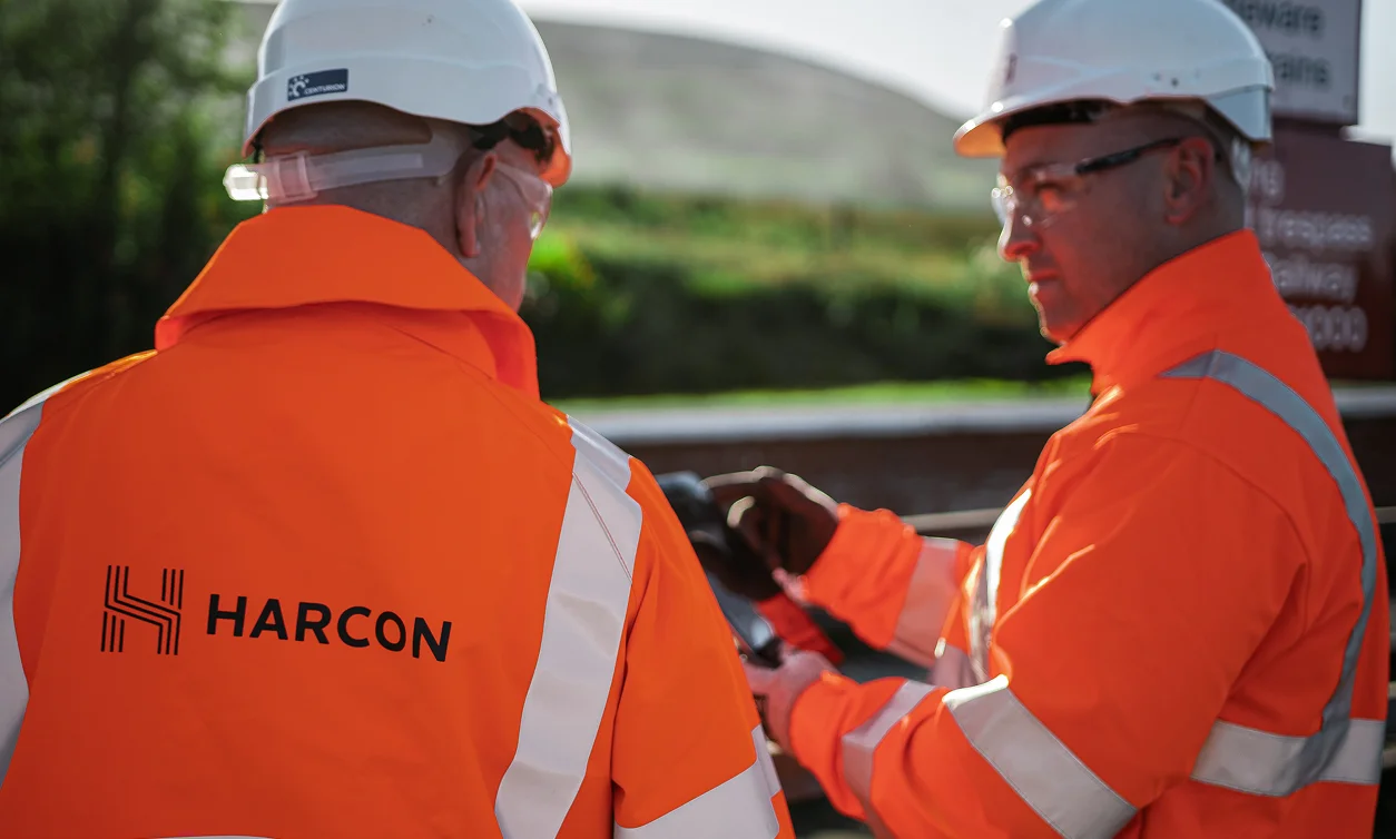 Two Harcon consultants in hard hats and hi vis talking on site beside the railway
