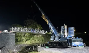 crane lifting a bridge into place over a railway line